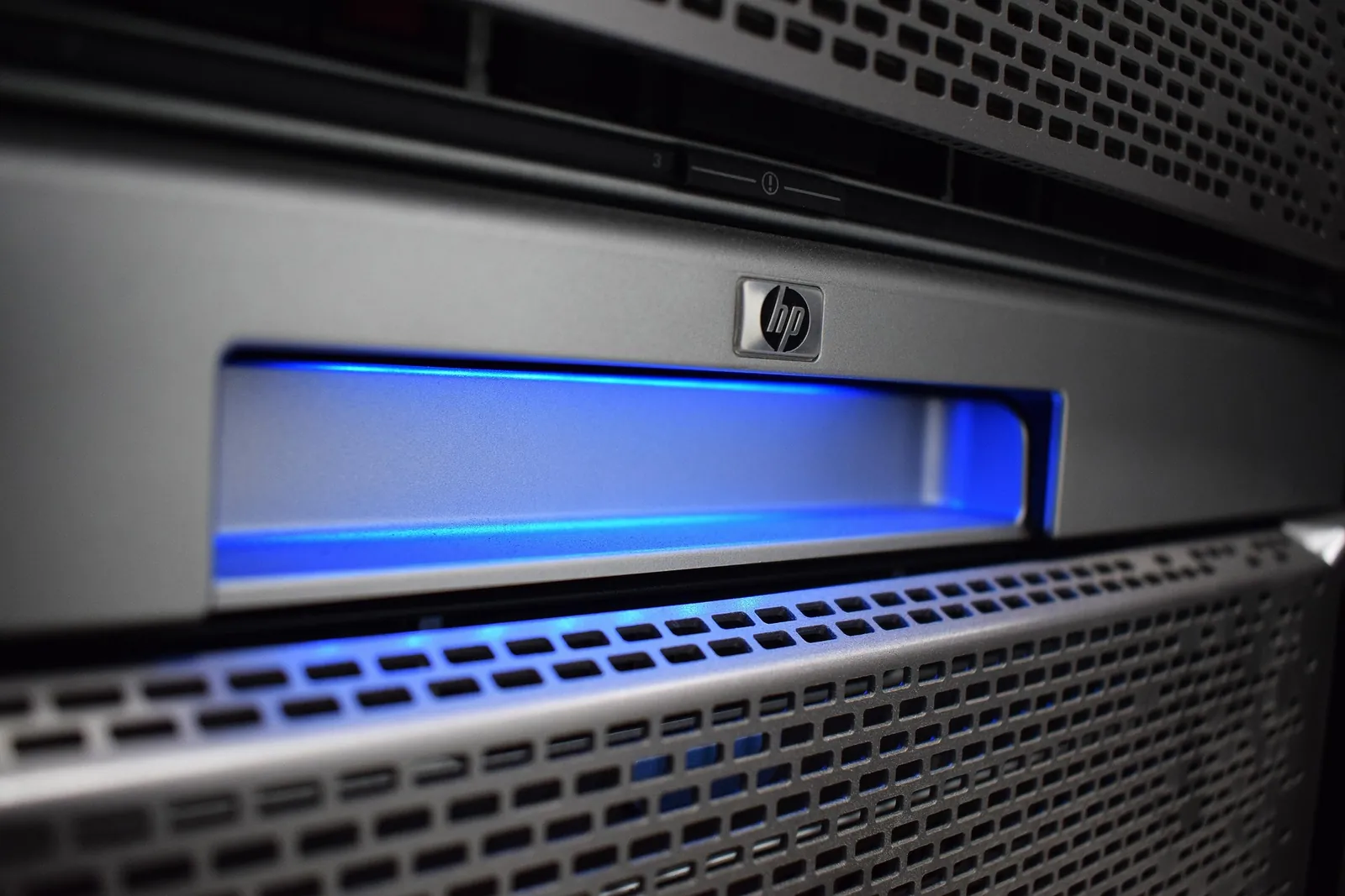 Face d’un serveur en baie avec grille de ventilation et un voyant bleu allumé