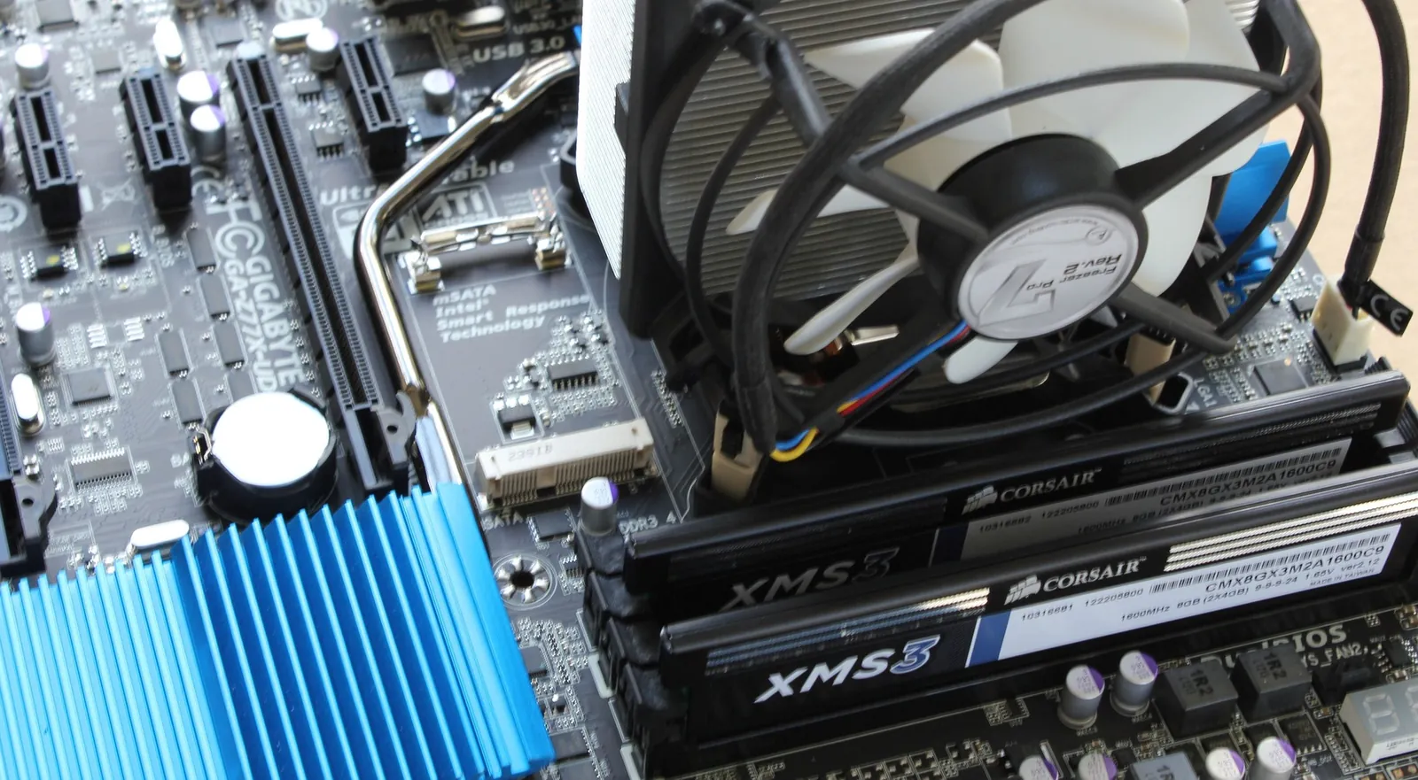 Intérieur d’un PC ouvert : carte mère, dissipateur avec ventilateur et deux barrettes de mémoire